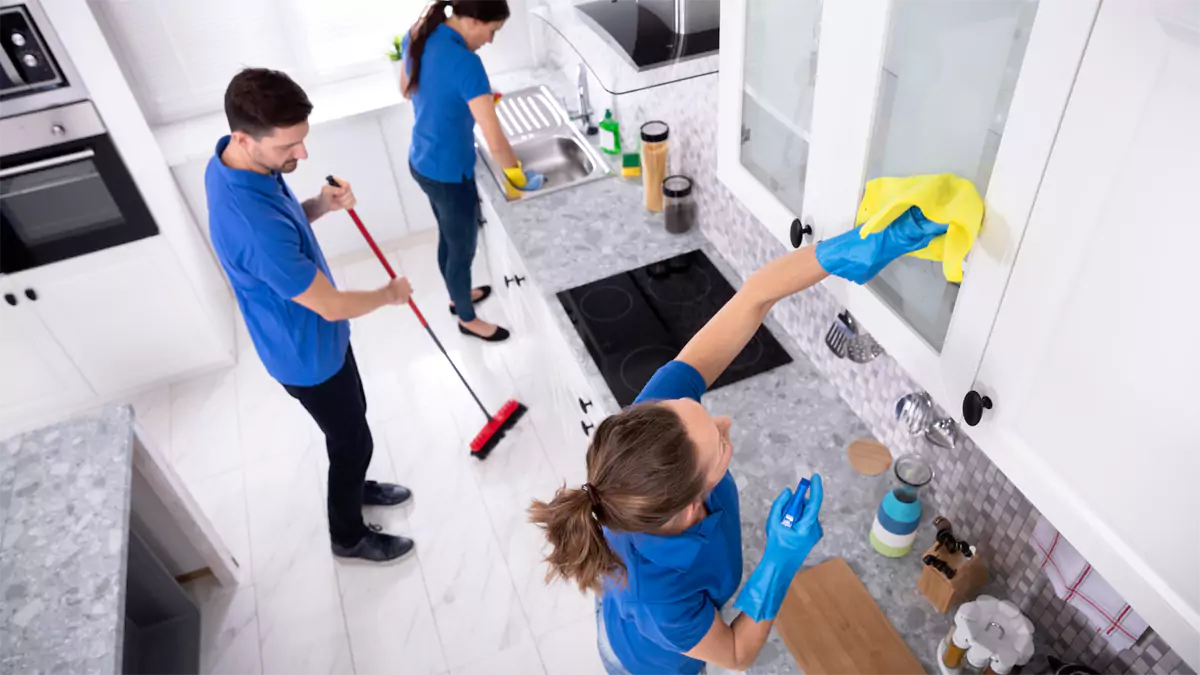 A StrongHold team working through a kitchen together - mopping, sink and cabinet fronts