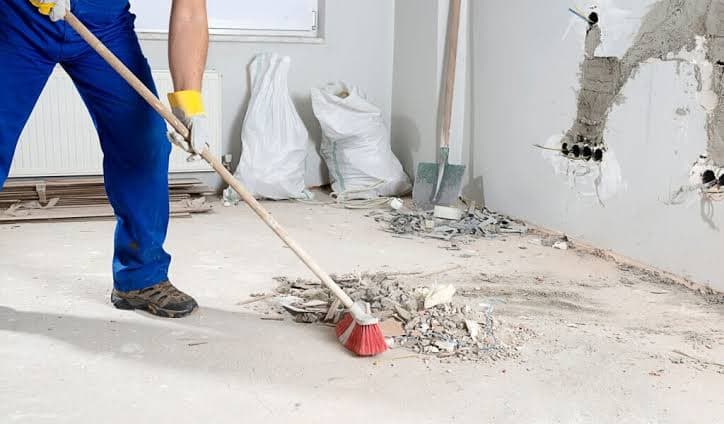 Operative sweeping rubble and fit-out debris from a bare concrete floor
